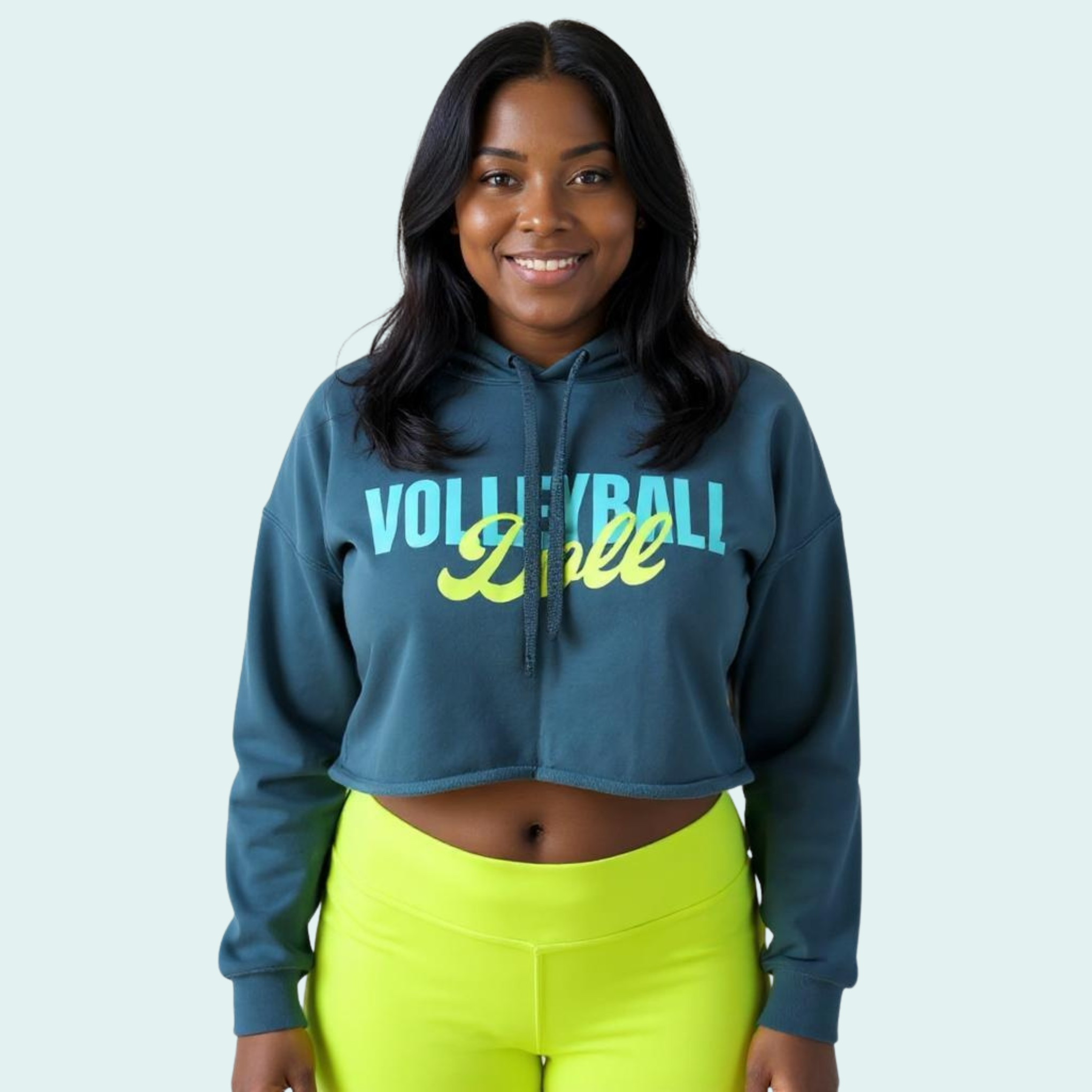 Female wearing a blue-green cropped hoodie with 'Volleyball Doll' text in bright light blue and yellow-green text across the front